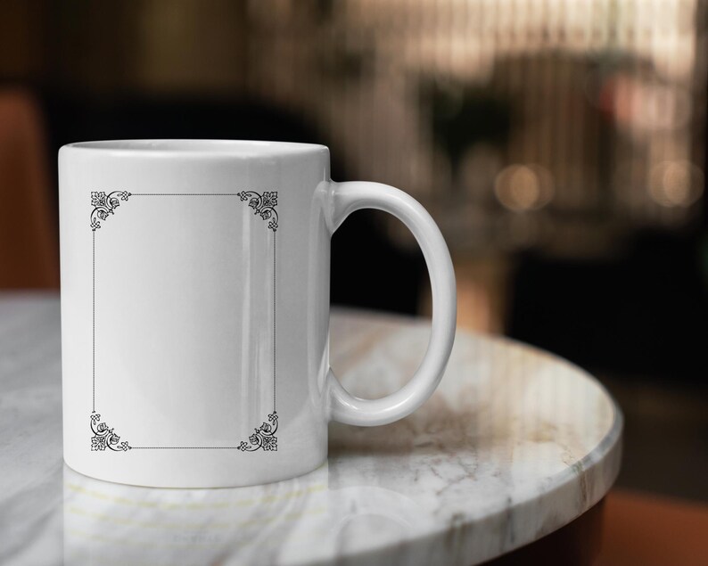 May include: White ceramic mug with a black decorative border around a blank space. The mug is sitting on a white marble surface.
