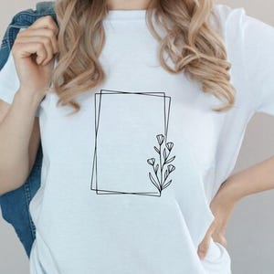 May include: A white t-shirt with a simple black line drawing of a square frame with a small floral design inside.