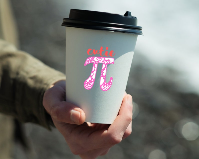 K&ouml;nnte beinhalten: Ein wei&szlig;er To-Go-Becher mit schwarzem Deckel. Der Becher hat ein pinkfarbenes und wei&szlig;es Design mit dem mathematischen Symbol Pi und dem Wort "cutie" dar&uuml;ber.