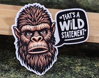 May include: A die-cut sticker featuring a detailed illustration of a brown, hairy creature resembling a Bigfoot or ape with intense eyes. To the right, a black speech bubble contains the white text, "THAT'S A WILD STATEMENT" in bold letters.