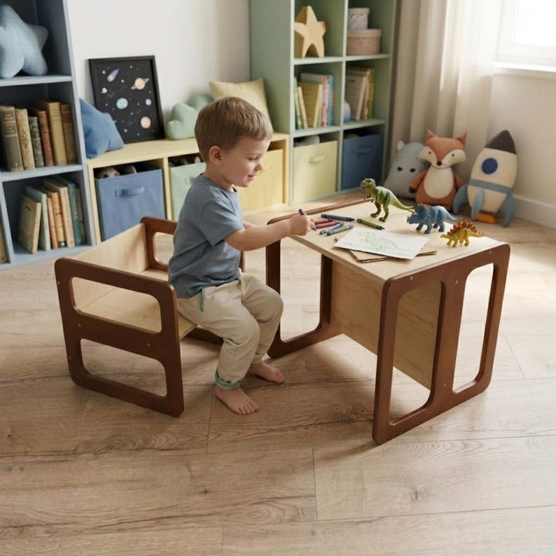 May include: A child's wooden desk and chair set with a light wood tabletop and dark brown legs. The child is drawing with crayons on a piece of paper. Toy dinosaurs are on the desk. The set is in a child's playroom.