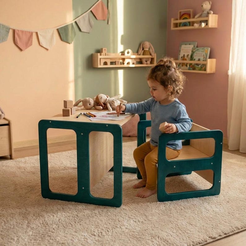 May include: A child's wooden table and chair set with a teal frame and natural wood tabletop and seat. The child is drawing on paper with colored pencils. The room has a neutral color palette with decorative shelves and a banner.