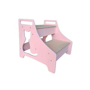 Op de afbeelding: Roze houten huisdierentrap met twee treden en een kattenuitsparing aan de zijkant. De treden hebben een natuurlijk houten oppervlak.