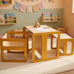 May include: A child's wooden table and chair set in a light brown color. The table has a rectangular top and square legs with cut-out sections. The chair has a similar design. The set is on a cream-colored rug.