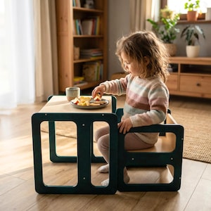 May include: A child's wooden table and chair set in a teal finish. The table has a light-colored top, and the chair is integrated into the design. The child is seated at the table, eating fruit from a small plate. The set is designed for young children.
