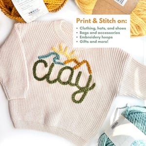 Pode incluir: Um su&eacute;ter de malha bege com a palavra "clay" bordada em fio verde, azul, amarelo e laranja. O texto "Imprima e costure em:" est&aacute; escrito acima do su&eacute;ter, seguido de uma lista de itens em que o design pode ser costurado, incluindo roupas, chap&eacute;us, sapatos, bolsas, acess&oacute;rios, argolas de bordado e presentes.