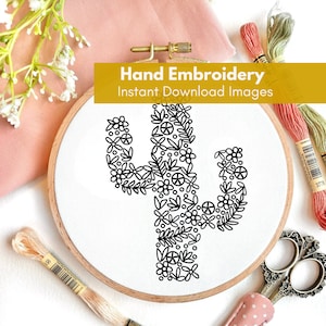 May include: A black and white embroidery design of a cactus with flowers and peace signs on a white fabric in a wooden embroidery hoop. The hoop is surrounded by embroidery floss and scissors.