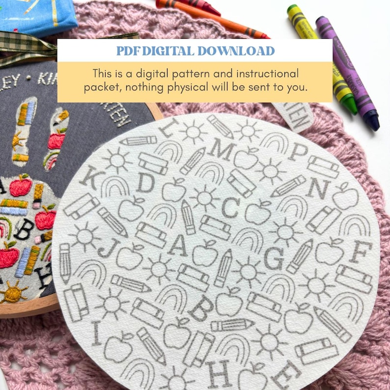 May include: A circular white fabric piece featuring a repeating gray line art pattern of letters, apples, pencils, suns, and rainbows. Beside it, a gray embroidery hoop displays a finished version of the design with colorful thread stitching.