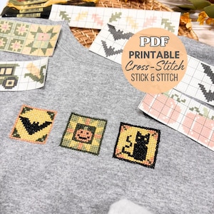 Puede incluir: Una superficie de tela gris jaspeado con varios patrones de punto de cruz impresos, incluyendo un murciélago negro, una calabaza y un gato negro. La imagen incluye un círculo con el texto PDF PRINTABLE Cross-Stitch STICK & STITCH.