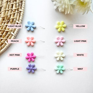 May include: Assortment of ten colorful daisy-shaped threaders in light blue, yellow, peach, light pink, hot pink, white, purple, and mint.