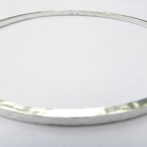 May include: A silver bangle bracelet with a hammered finish.