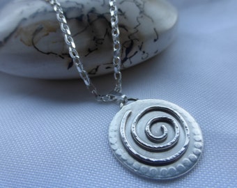 May include: A silver necklace with a round pendant featuring a textured spiral design.