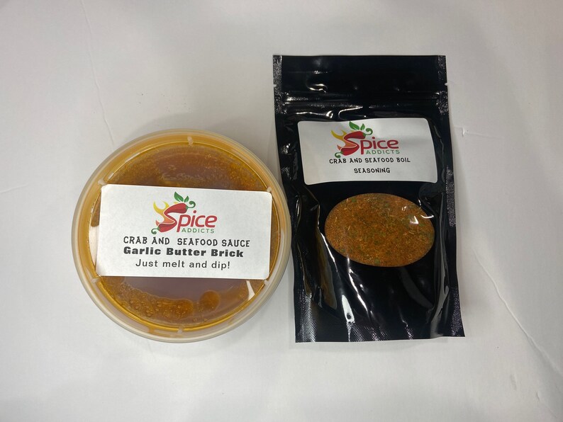 May include: Two containers of crab and seafood seasoning. One container is a clear plastic jar with a red and yellow label that reads "Spice Addicts Crab and Seafood Sauce Garlic Butter Brick Just melt and dip!" The other container is a black plastic bag with a red and yellow label that reads "Spice Addicts Crab and Seafood Boil Seasoning".