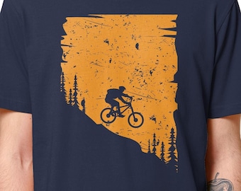 May include: A navy blue t-shirt with a distressed orange graphic of a person riding a mountain bike down a hill. The graphic includes trees and a sunset.