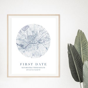 May include: A framed print with a blue and white map of Manchester, England. The text "FIRST DATE" is printed below the map, along with the city and coordinates.