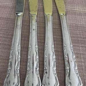 以下が含まれることがあります： バラのデザインが施された装飾的なハンドルが付いた、銀製のディナーナイフ4本です。