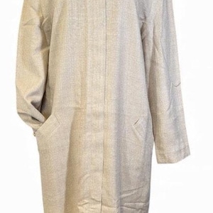 May include: A light beige, long coat with a round neckline and a single gold button closure. The coat features two front pockets and long sleeves. The fabric has a subtle textured appearance, and the coat is displayed on a mannequin.