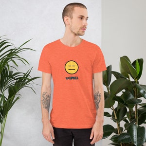 May include: A bright orange t-shirt with a yellow smiley face with a black outline and two horizontal lines for eyes. The text "#1F811" is printed below the smiley face.
