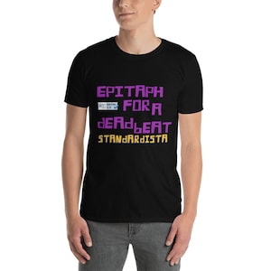 Könnte beinhalten: Ein schwarzes T-Shirt mit dem Text "EPITAPH FOR A DEADBEAT STANDARDISTA" in Lila und Gelb. Ein kleines blaues und weißes Symbol mit dem Text "W3C XHTML 1.0" befindet sich über dem Text.