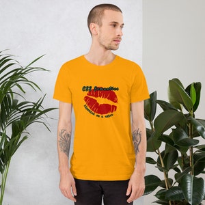 Peut inclure: Un t-shirt jaune avec un imprimé de lèvres rouges et le texte "CSS Semantics" et "Lipstick on a code?" en noir.