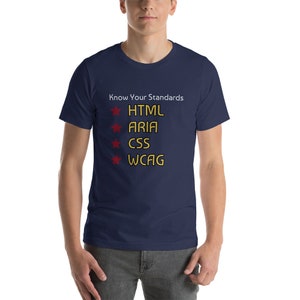 Könnte beinhalten: Ein marineblaues T-Shirt mit dem Text "Know Your Standards" und einer Liste von Web-Barrierefreiheitsstandards: HTML, ARIA, CSS, WCAG. Jeder Standard wird von einem roten Stern vorangestellt.