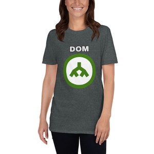 Puede incluir: Una camiseta gris oscuro jaspeada con un círculo verde y un símbolo blanco. El texto "DOM" está impreso en blanco sobre el círculo.