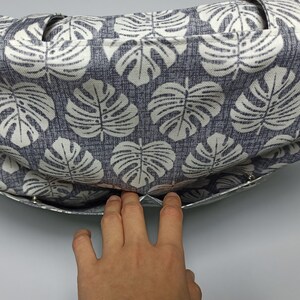 May include: A grey and white fabric tote bag with a monstera leaf pattern. The bag is open and the lining is visible.