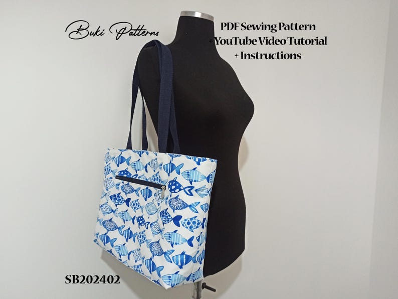 May include: A white tote bag with a blue fish pattern. The bag has a zipper closure and a black handle. The text "Buki Patterns" and "PDF Sewing Pattern YouTube Video Tutorial + Instructions" is visible on the image. The product code "SB202402" is also visible.