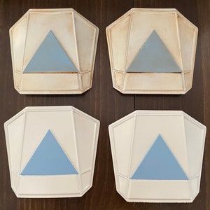 May include: Four white ceramic wall sconces with a geometric design. Each sconce has a light blue triangular shape in the center.