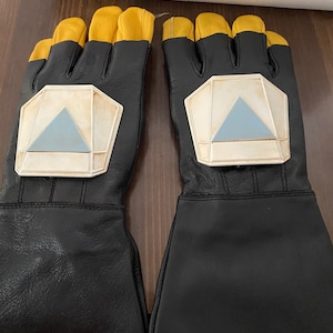 May include: A pair of black leather gloves with yellow accents and a white and blue geometric design on the back of each hand.