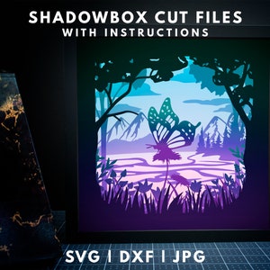 Puede incluir: Un diseño de archivo de corte para shadowbox que presenta una mariposa en un entorno de bosque. El diseño incluye montañas, árboles y un río. La mariposa está en vuelo y tiene un esquema de color morado y azul. El diseño es perfecto para crear una shadowbox única y hermosa.