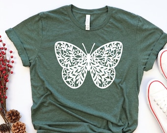 May include: A green t-shirt with a white butterfly design. The butterfly has a detailed, intricate pattern.