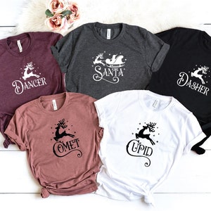 May include: Five t-shirts with different reindeer designs and names. The shirts are in various colors, including maroon, gray, black, and white. The designs feature reindeer with names like "Dancer", "Dasher", "Comet", "Cupid", and "Santa".