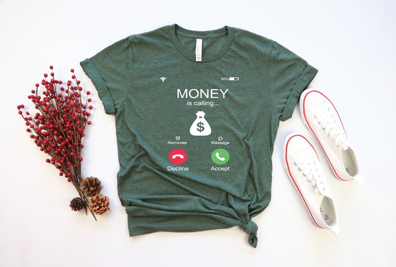 K&ouml;nnte beinhalten: Ein gr&uuml;nes T-Shirt mit einer wei&szlig;en Grafik eines Telefonbildschirms, auf dem "MONEY is calling..." steht, mit einem Geldbeutelsymbol und Kn&ouml;pfen mit der Aufschrift "Decline" und "Accept".