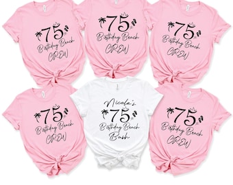 May include: Six pink and one white t-shirts with black text. The shirts say "*75* Birthday Beach Crew" and "Nicole's *75* Birthday Beach Bash".