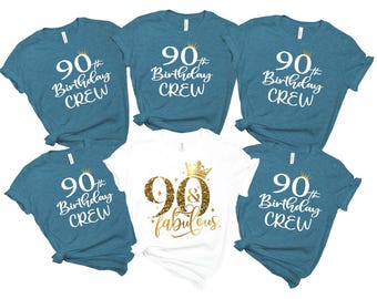 Puede incluir: Cinco camisetas de color verde azulado con texto blanco que dice 90th Birthday CREW y una pequeña corona dorada, más una camiseta blanca con texto de purpurina dorada 90 & fabulous y una corona grande. Todas tienen mangas cortas.