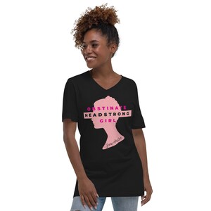 May include: Black v-neck t-shirt featuring a pink silhouette of a woman's head and the text "Obstinate Headstrong Girl" in pink. The text "Jane Austen" is written in smaller font below the silhouette.