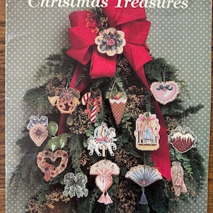 May include: A craft pattern book titled Victorian Christmas Treasures Vol. 25 by Douglas Designs. The cover features a dark green background with white dots, displaying various cross-stitch ornaments hanging on a pine tree with a large red bow.