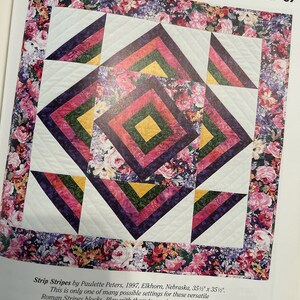 K&ouml;nnte beinhalten: Eine Steppdecke aus bunten Stoffquadraten in den Farben Rosa, Lila, Gr&uuml;n und Gelb. Die Quadrate sind in einem geometrischen Muster angeordnet, was ein optisch ansprechendes Design ergibt. Die Steppdecke ist von einem Rand aus Blumenstoff umgeben.