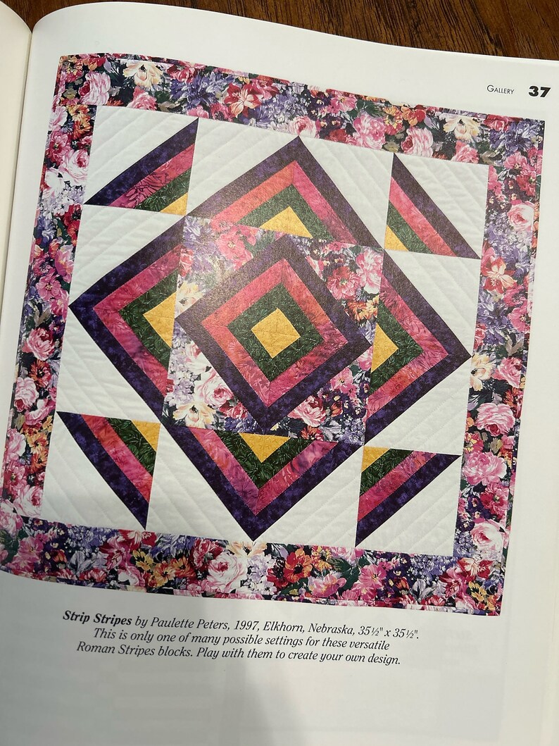 K&ouml;nnte beinhalten: Eine Steppdecke aus bunten Stoffquadraten in den Farben Rosa, Lila, Gr&uuml;n und Gelb. Die Quadrate sind in einem geometrischen Muster angeordnet, was ein optisch ansprechendes Design ergibt. Die Steppdecke ist von einem Rand aus Blumenstoff umgeben.