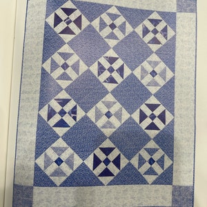 K&ouml;nnte beinhalten: Ein Quiltmuster namens "Blue Shoo Fly", hergestellt aus blauem und wei&szlig;em Stoff. Der Quilt ist 107 cm x 132 cm gro&szlig;. Der Quilt ist aus einem traditionellen Block gefertigt, der aus Streifen zusammengesetzt ist. Der Quilt ist aus vier verschiedenen Blaut&ouml;nen gefertigt.