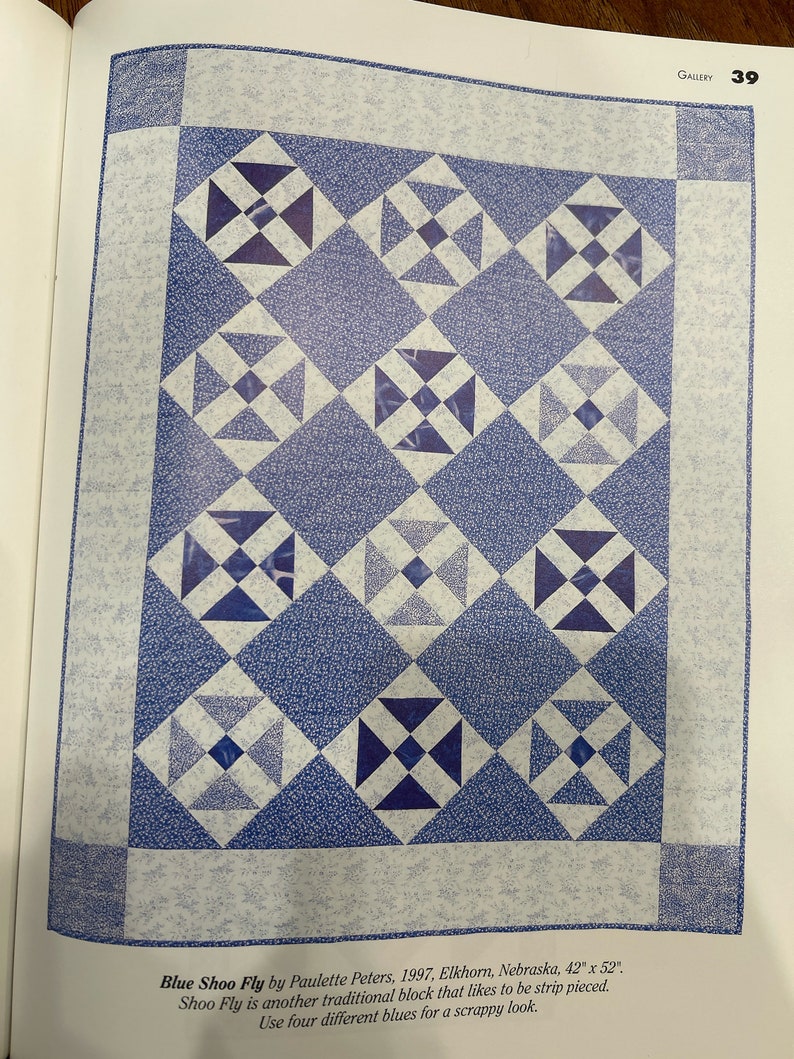 K&ouml;nnte beinhalten: Ein Quiltmuster namens "Blue Shoo Fly", hergestellt aus blauem und wei&szlig;em Stoff. Der Quilt ist 107 cm x 132 cm gro&szlig;. Der Quilt ist aus einem traditionellen Block gefertigt, der aus Streifen zusammengesetzt ist. Der Quilt ist aus vier verschiedenen Blaut&ouml;nen gefertigt.