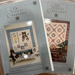Könnte beinhalten: Zwei Nähheftchen von "The Stitch Connection" werden gezeigt. Eines zeigt einen Baby-Quilt mit einem Teddybären und Blöcken. Das andere zeigt einen Quilt mit einem geometrischen Muster. Beide haben einen hellblauen Hintergrund mit Sternakzenten.