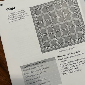 K&ouml;nnte beinhalten: Ein Quiltmuster mit einem karierten Design. Der Quilt besteht aus neun Bl&ouml;cken, die jeweils eine andere Farbe haben. Die Bl&ouml;cke sind von einem Paspel umgeben, einem schmalen Stoffstreifen, der die Bl&ouml;cke trennt. Der Quilt ist mit einem Zackenrand versehen.