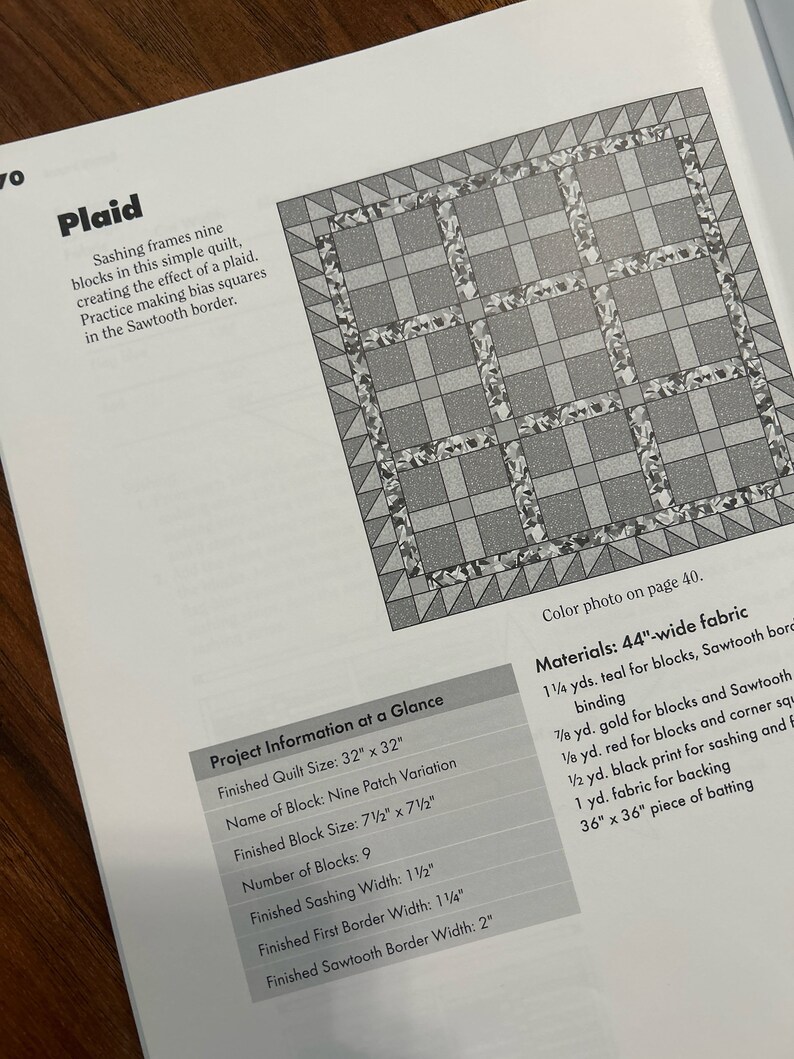 K&ouml;nnte beinhalten: Ein Quiltmuster mit einem karierten Design. Der Quilt besteht aus neun Bl&ouml;cken, die jeweils eine andere Farbe haben. Die Bl&ouml;cke sind von einem Paspel umgeben, einem schmalen Stoffstreifen, der die Bl&ouml;cke trennt. Der Quilt ist mit einem Zackenrand versehen.