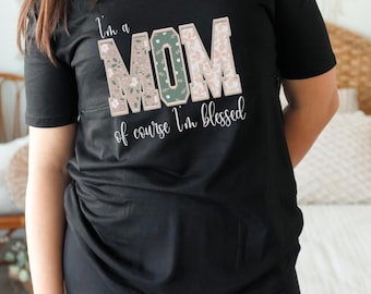 May include: Black t-shirt with a floral design that says "I'm a MOM of course I'm blessed".
