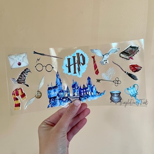 May include: A sheet of clear vinyl stickers featuring Harry Potter themed illustrations. The stickers include a Hogwarts castle, a golden snitch, a wand, a pair of glasses, a letter, a hat, a scarf, a tie, a key, a cauldron, a cup, a book, an owl, and a broom. The stickers are printed with the text "Simple Daisy Finds".