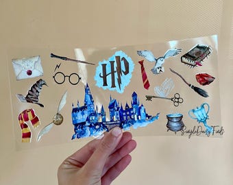 May include: A sheet of clear vinyl stickers featuring Harry Potter themed illustrations. The stickers include a Hogwarts castle, a golden snitch, a wand, a pair of glasses, a letter, a hat, a scarf, a tie, a key, a cauldron, a cup, a book, an owl, and a broom. The stickers are printed with the text "Simple Daisy Finds".