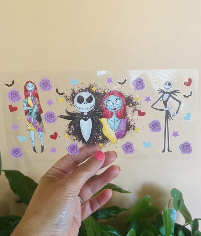 K&ouml;nnte beinhalten: Ein klarer Aufkleber mit Illustrationen von Jack Skellington und Sally aus The Nightmare Before Christmas. Der Aufkleber enth&auml;lt Bilder von Rosen, Herzen, Sternen und Flederm&auml;usen. Die Charaktere sind im Cartoon-Stil gehalten.
