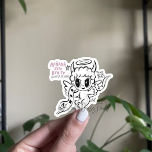 May include: A black and white sticker featuring a cartoon angel with a halo, horns, and a snake wrapped around its wings. The sticker has the text "Mañana Sera Bonito (Bichota Season)" in pink lettering.